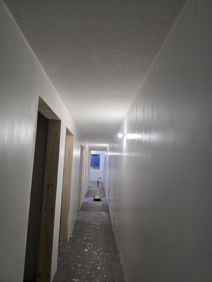 Chinook Glow drywall complete — corridor fully drywalled and primed
