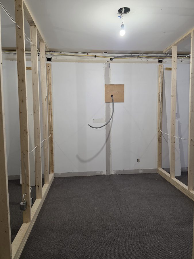 Red light therapy room before — framed walls and electrical rough-in with buck booster feed